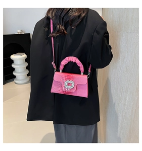 Vista dettagliata della borsa rosa con trama a coccodrillo e fibbia in strass su abito nero