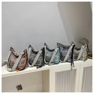 Multiple colors of woven tote bags with wide shoulder straps on a white cabinet