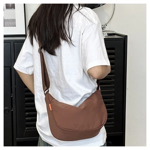 Brown nylon crescent bag detail showing side orange tag and adjustable wide strap