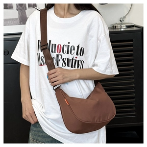 Detail view of a large brown nylon crescent bag with adjustable wide strap and orange label