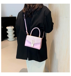 Detail of pink crossbody bag with glitter finish and golden H clasp on a black coat