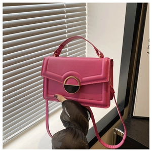 Detail of rose pink crossbody bag featuring geometric texture and gold ring buckle closure