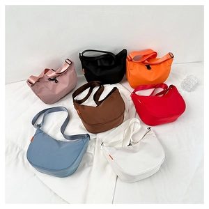 Flat lay of nylon crescent crossbody bags in seven vibrant colors with adjustable straps