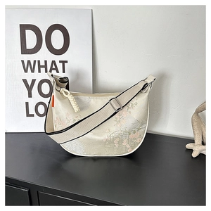 Detailed embroidery on a cream-colored crescent hobo bag with pink and green floral patterns
