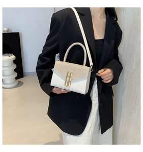 Detail of white contrast crossbody bag with gold glitter flap and metal bar decoration
