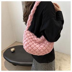 Détail du sac cabas rose matelassé avec anse tressée porté par un mannequin en intérieur