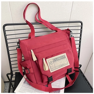 Dettaglio della borsa a tracolla in nylon rosso con patch fashion e tracolla regolabile