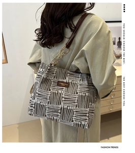 Detail of striped tote bag featuring brown rope texture and gold chain strap detail