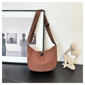 Detail of a brown waterproof oxford moon bag with wide shoulder strap and orange woven label