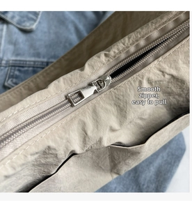 Gros plan sur le sac en nylon beige avec détail de fermeture éclair en métal argenté