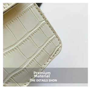 Detail of cream faux crocodile leather texture and precise stitching on chain bag
