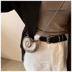Macro detail of silver shell-shaped metallic crossbody bag with fine snake chain strap
