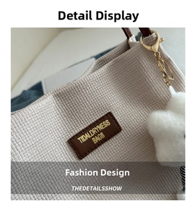 Detail of woven beige tote bag featuring brown leather logo tag and cloud plush charm