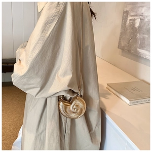 Close-up of a luxury gold shell-shaped nautilus mini bag with a fine chain strap