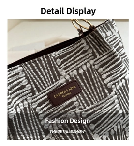 Detail of grey plaid textured fabric tote bag with brown leather logo and gold metal handle