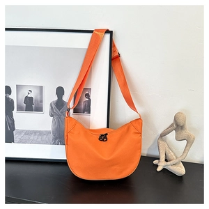 Detail of orange nylon dumpling bag featuring black dual zippers and adjustable strap