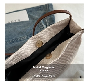 Detail view of woven shoulder bag featuring premium golden magnetic snaps for closure
