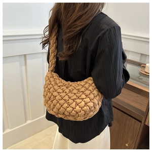 Sac bandoulière marron matelassé à texture bulles porté par un mannequin en décor chic