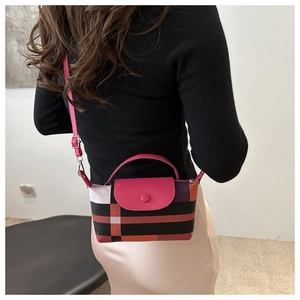 Détail du mini sac à carreaux avec poignée rose porté sur l'épaule d'une femme