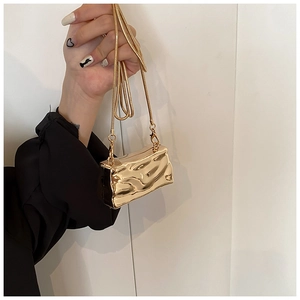 Detailed macro of gold metallic shell bag with liquid texture and dainty chain strap
