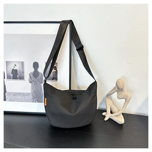 Close-up of waterproof black hobo bag with adjustable strap and orange side label
