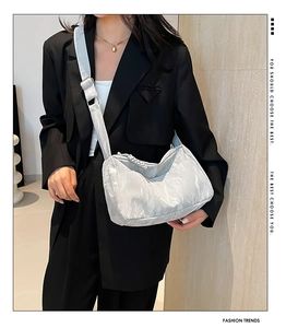 Detail of light grey pleated tote bag with adjustable strap on a black suit model