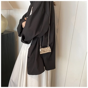 Detail of a mini metallic shell-shaped bag with irregular pleats and elegant chain strap