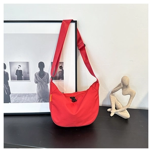 Close-up of a vibrant red crescent-shaped shoulder bag with durable nylon and adjustable strap