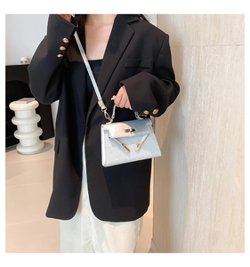 Detalle de un bolso plateado con purpurina y asa metálica dorada puesto en modelo