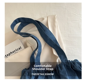 Close-up of wide denim shoulder strap with visible twill texture on a blue bucket bag