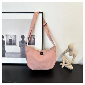 Detail of dusty pink crescent crossbody bag with double zippers and adjustable strap