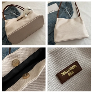 Detail view of woven tote bag with brown straps, magnetic clasp, and plush charm