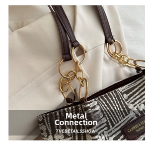 Detailed close-up of golden metal buckle and leather strap on plaid fabric tote bag