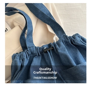Detail of drawstring closure and stitching on dark blue large denim bucket shoulder bag