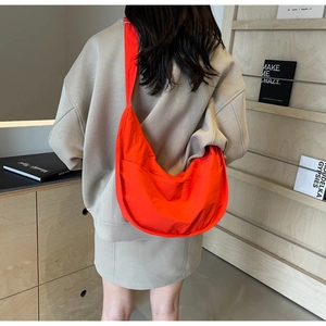 Vue détaillée du dos d'un grand sac croissant orange vif porté par un mannequin en intérieur