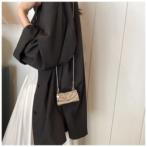 Detail of molten-style metallic mini bag with chain strap on model in black shirt