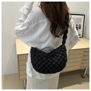 Détail du sac nuage noir matelassé avec bandoulière tressée épaisse porté par un mannequin