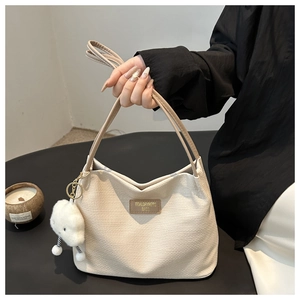 Détail du sac cabas tissé crème avec patch logo en cuir brun et breloque nuage