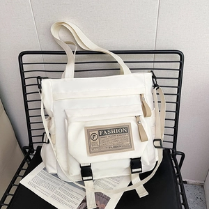 Borsa a tracolla bianca in nylon di grande capacità con fibbia nera su una sedia