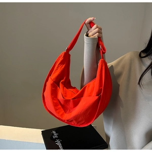 Détail d'un sac demi-lune rouge vif en nylon résistant avec une large bandoulière souple