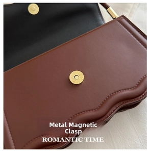 Detailansicht der matten Goldschnalle und der Wellenkantennaht an einer braunen Ledertasche