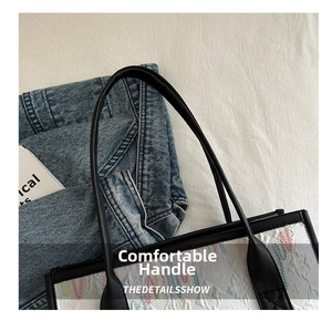 Detail of white tote bag featuring colorful embroidery and slim black leather handles