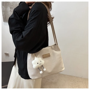 Close-up of beige tote bag with waffle texture and a cute white cloud plush pendant