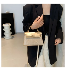 Dettaglio della borsa Kelly oro champagne glitterata indossata da modella in tailleur