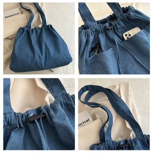 Detail view of denim tote bag showing drawstring closure and side pockets for storage