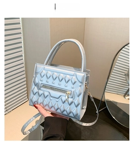 Detail of silver quilted crossbody bag featuring dual round handles and metallic zipper