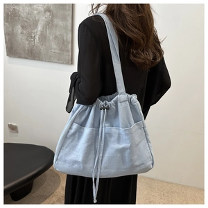 Detail of light blue canvas tote bag featuring drawstring closure and front pockets