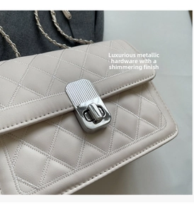 Close-up of quilted ivory leather bag with silver wavy twist lock and chain strap