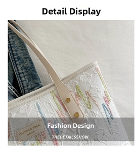 Detail of white tote bag featuring colorful wavy embroidery and premium leather handles
