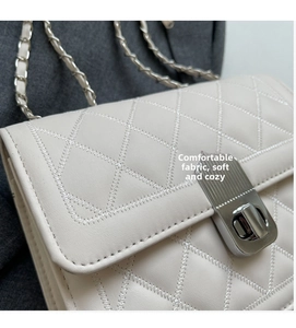 Detail of cream quilted crossbody bag featuring elegant stitching and silver twist lock